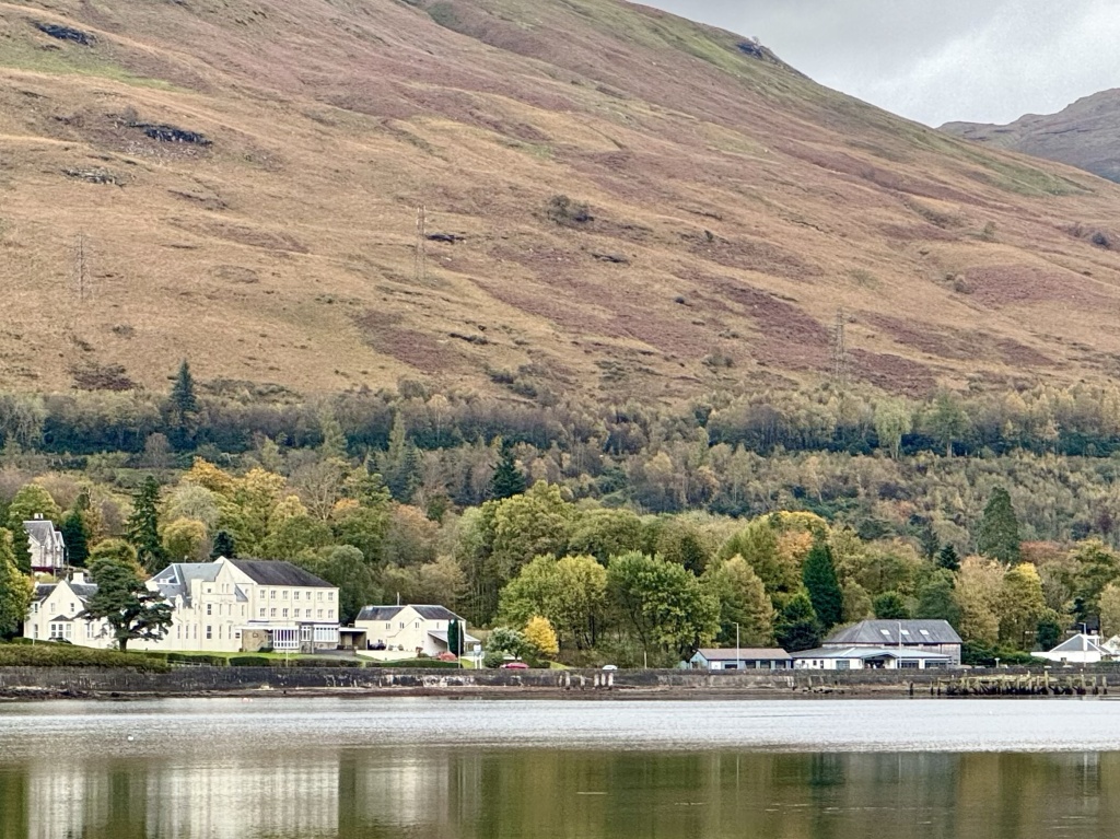 View of buildings at base of step hill, overlooking loch