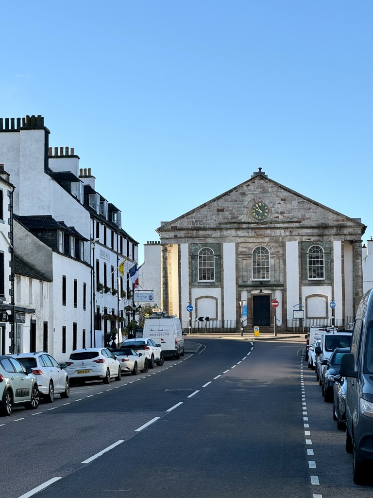 Looking up the high street towards the town hall, below a clear blue sky.