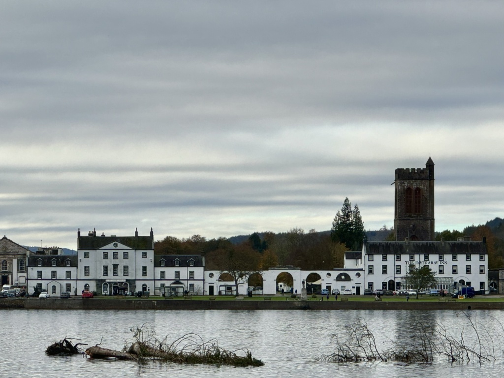 White faced buildings lining the street overlooking the loch, below grey sky.
